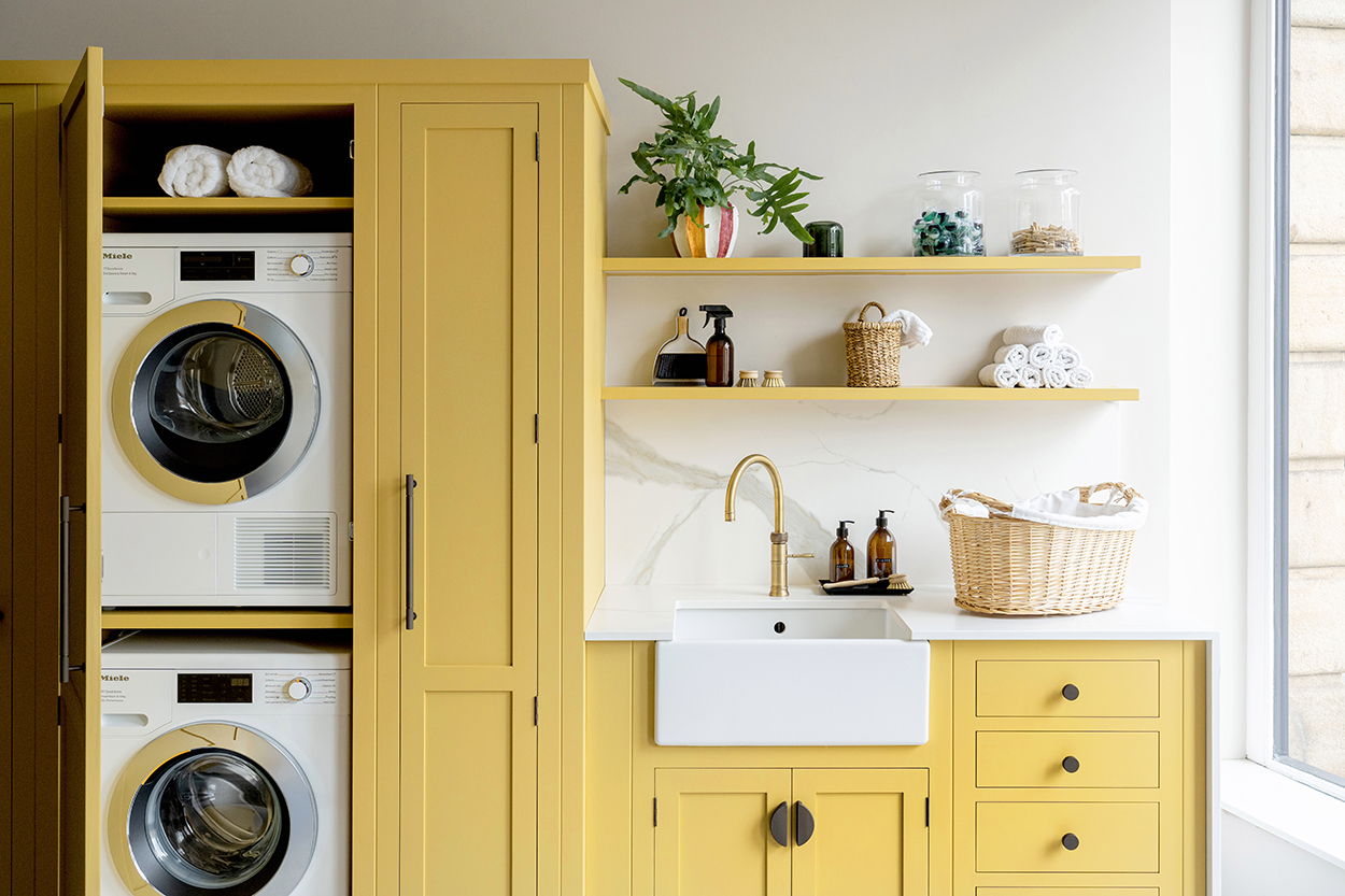 Yellow utility room with Belfast sink, stacked washer dryer and open shelving