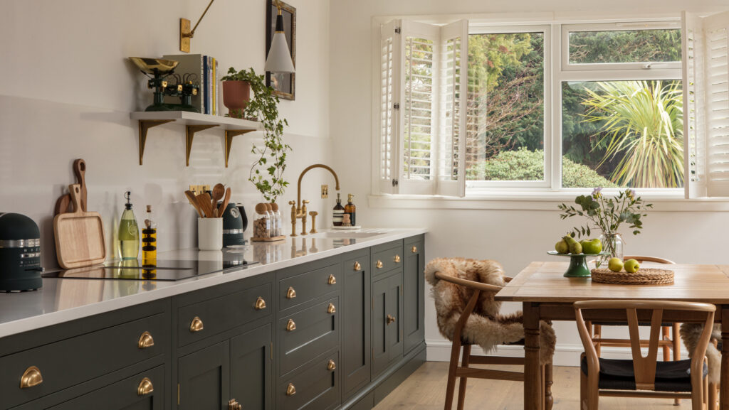 Dark green small kitchen design with dark and white colour scheme, gold hardware for warmth and quartz worktops for brightness