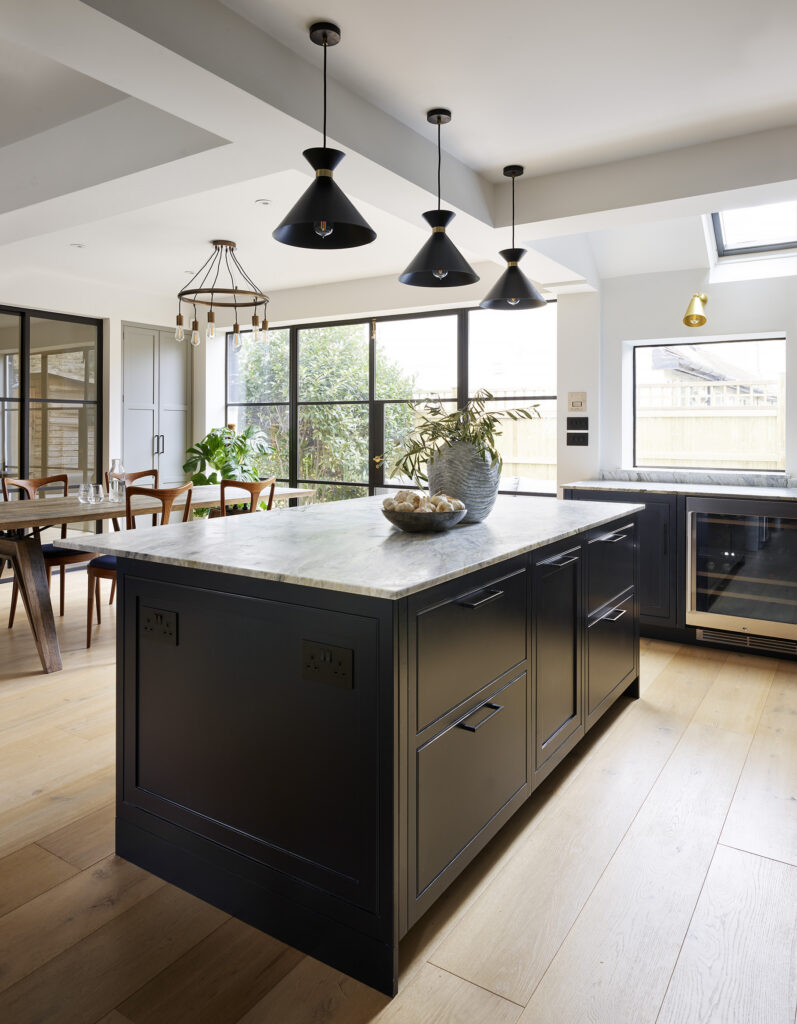 Navy blue kitchen with large island featuring pendant lighting and marble worktop