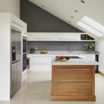 Walnut kitchen island with white worktop surrounded by white Linear kitchen cabinetry