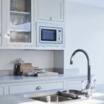 White Arbor kitchen cabinetry featuring a white kitchen island worktop with silver sink and tap