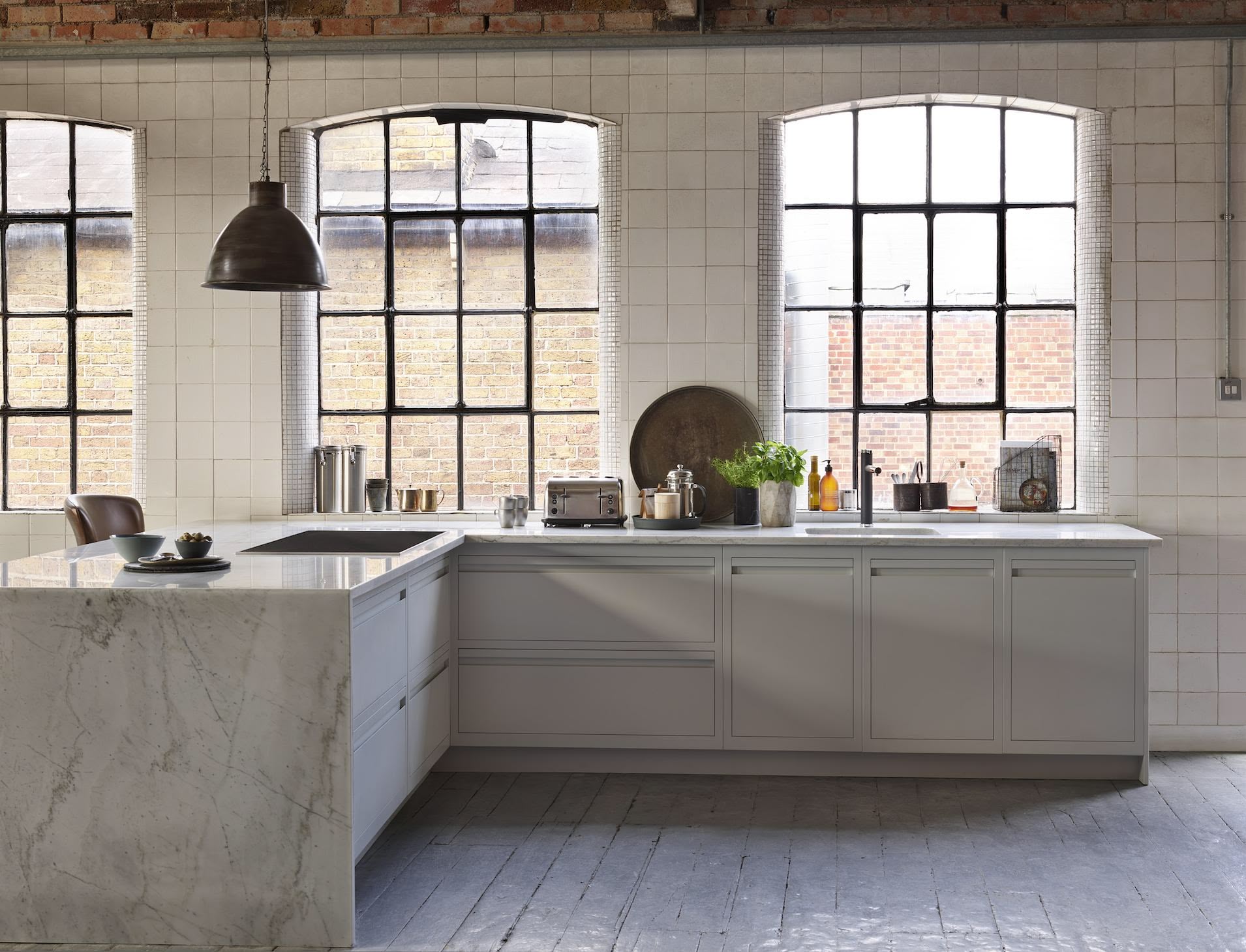 Industrial style kitchen with cream Linear Edge kitchen cabinetry and marble worktop