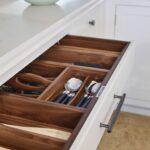 Light grey kitchen drawer with walnut interior open to show organised cutlery storage