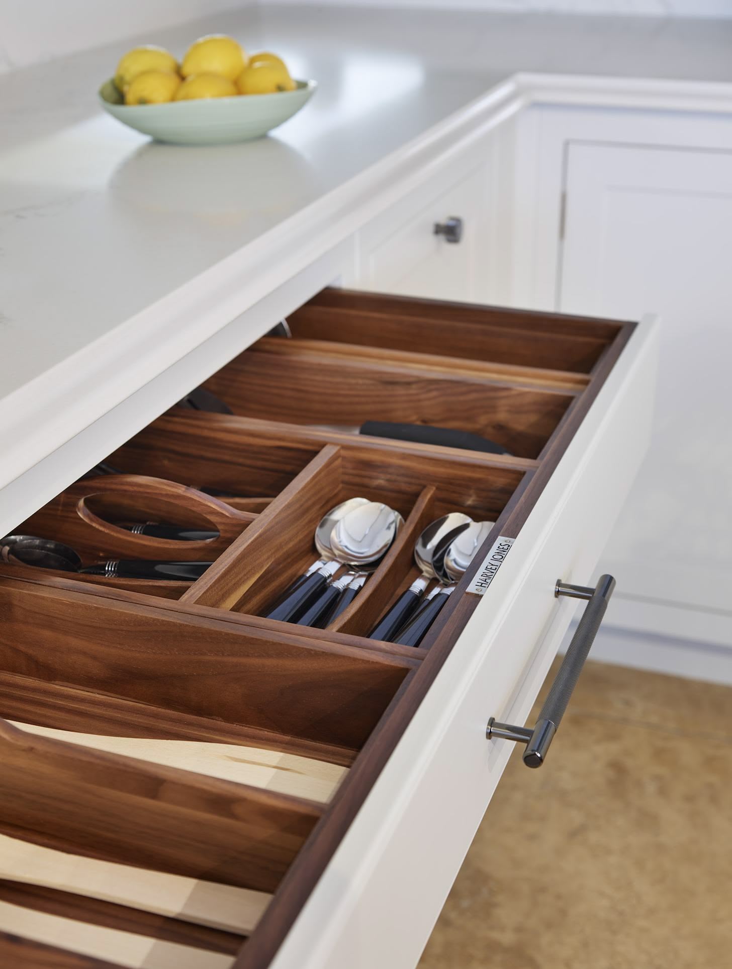 Light grey kitchen drawer with walnut interior open to show organised cutlery storage