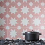 Decorative pink and white tiling behind a silver cooker top