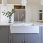 Grey kitchen island with Arbor cabinetry design featuring a white basin sink with silver tap