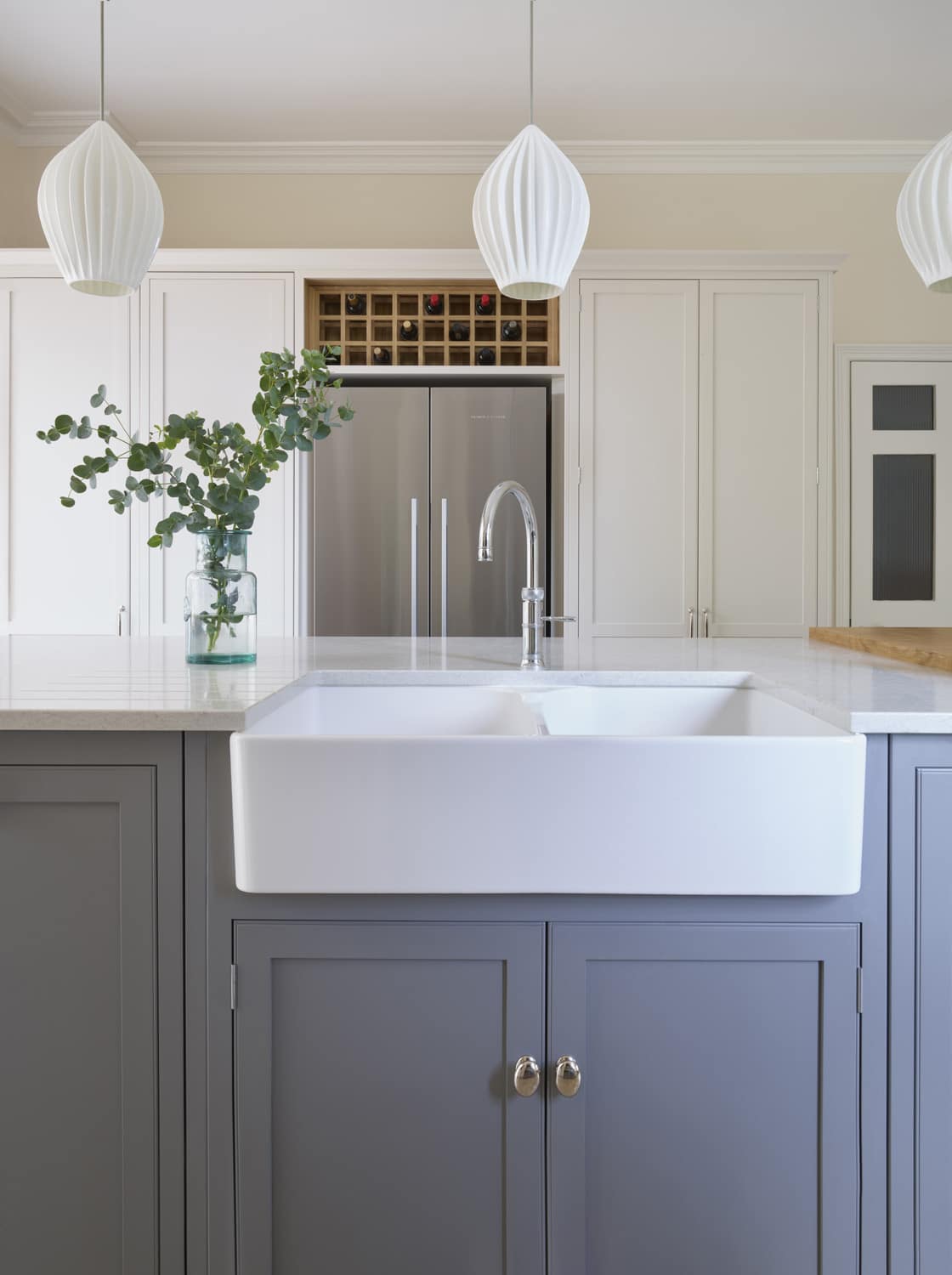 Grey kitchen island with Arbor cabinetry design featuring a white basin sink with silver tap