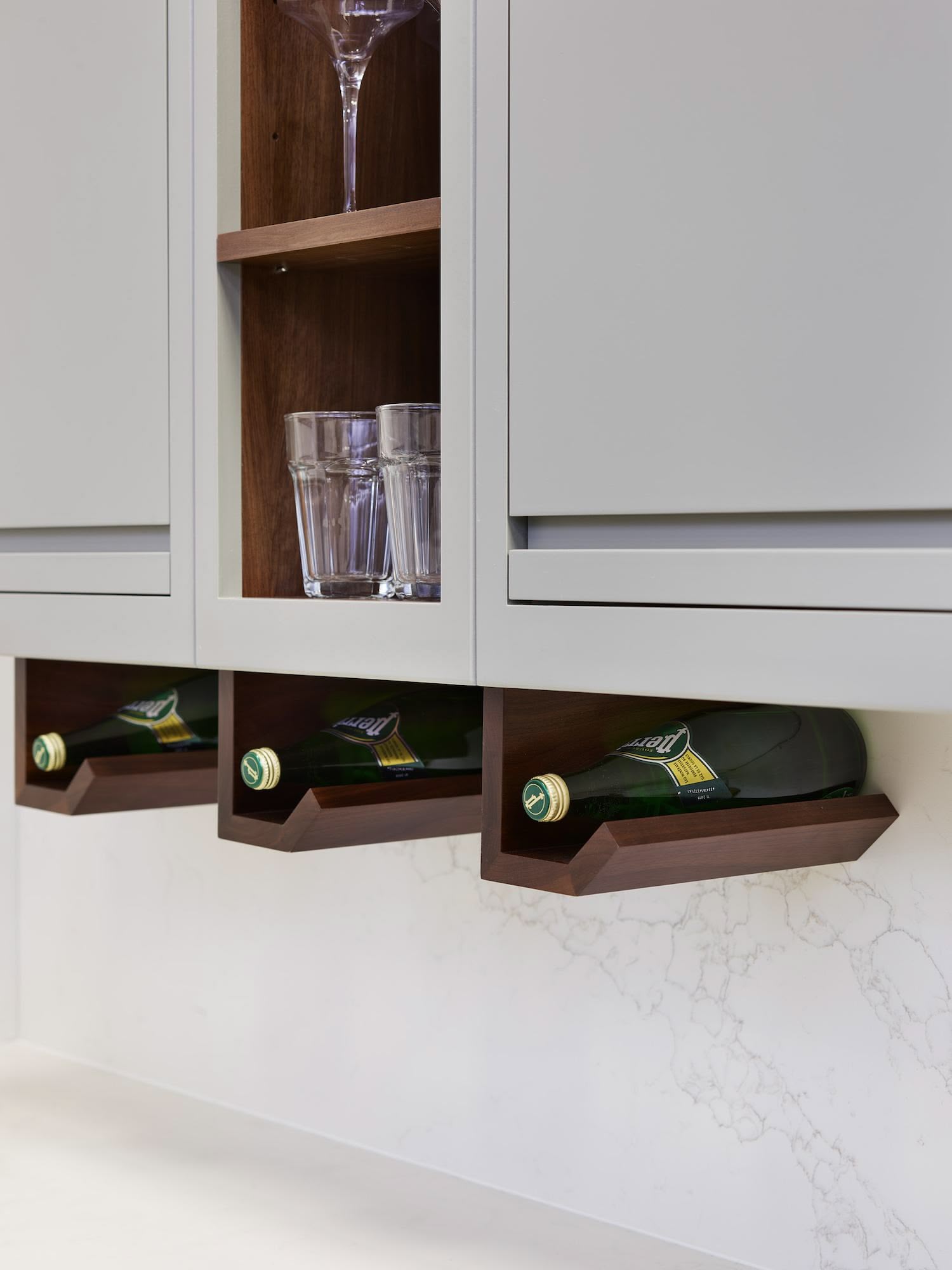 Green-grey kitchen cabinetry featuring dark oak wine storage underneath