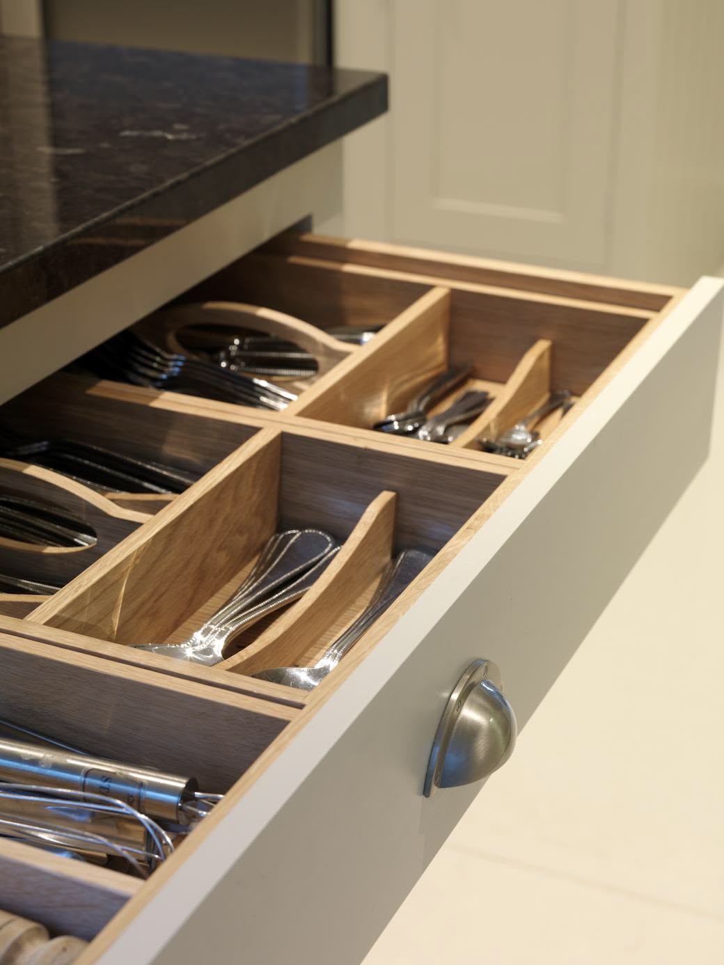 Grey kitchen drawer with oak interior open to show organised cutlery storage
