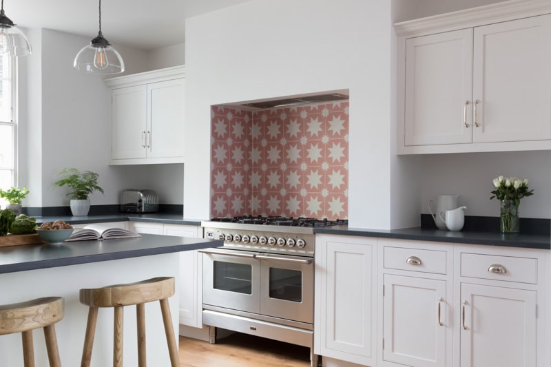 White Arbor kitchen cabinetry and black worktops with decorative tiling around the cooker area