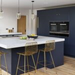 Blue kitchen island with white worktop and gold stools