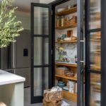Dark kitchen larder open to reveal organised sotrage