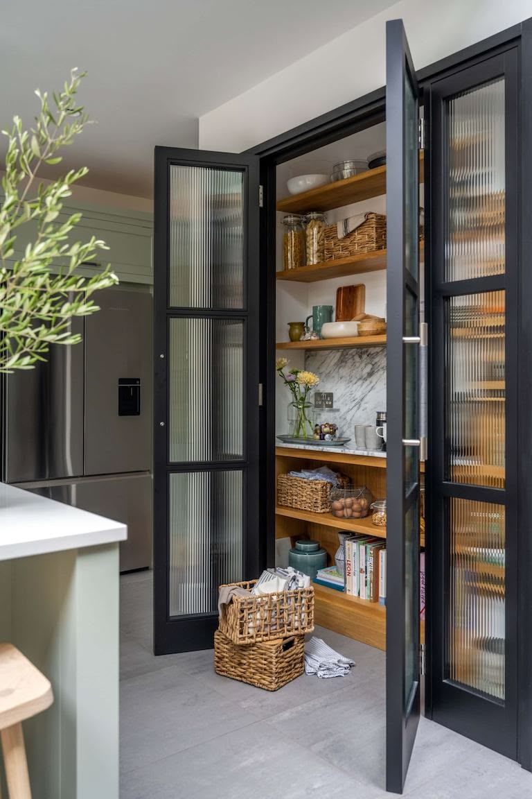 Dark kitchen larder open to reveal organised sotrage