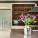 Grey kitchen island worktop featuring Shaker kitchen cabinetry and exposed brick wall