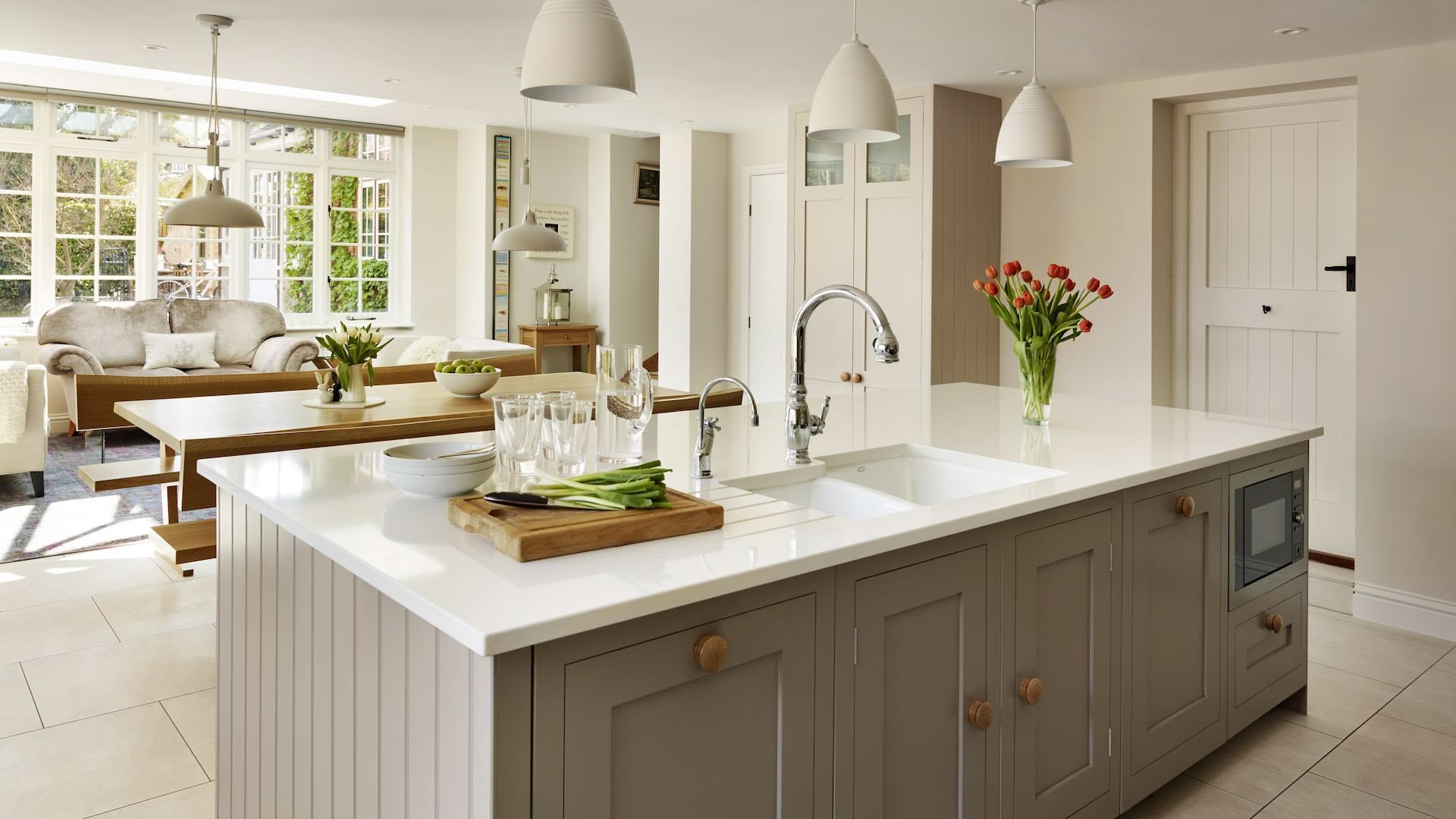 Beige SHaker kitchen island with white worktop and integrated sink overlooking open plan dining area