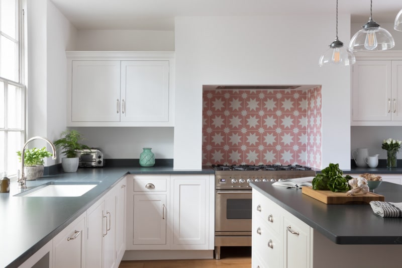 White Arbor kitchen cabinetry and black worktops with decorative tiling around the cooker area