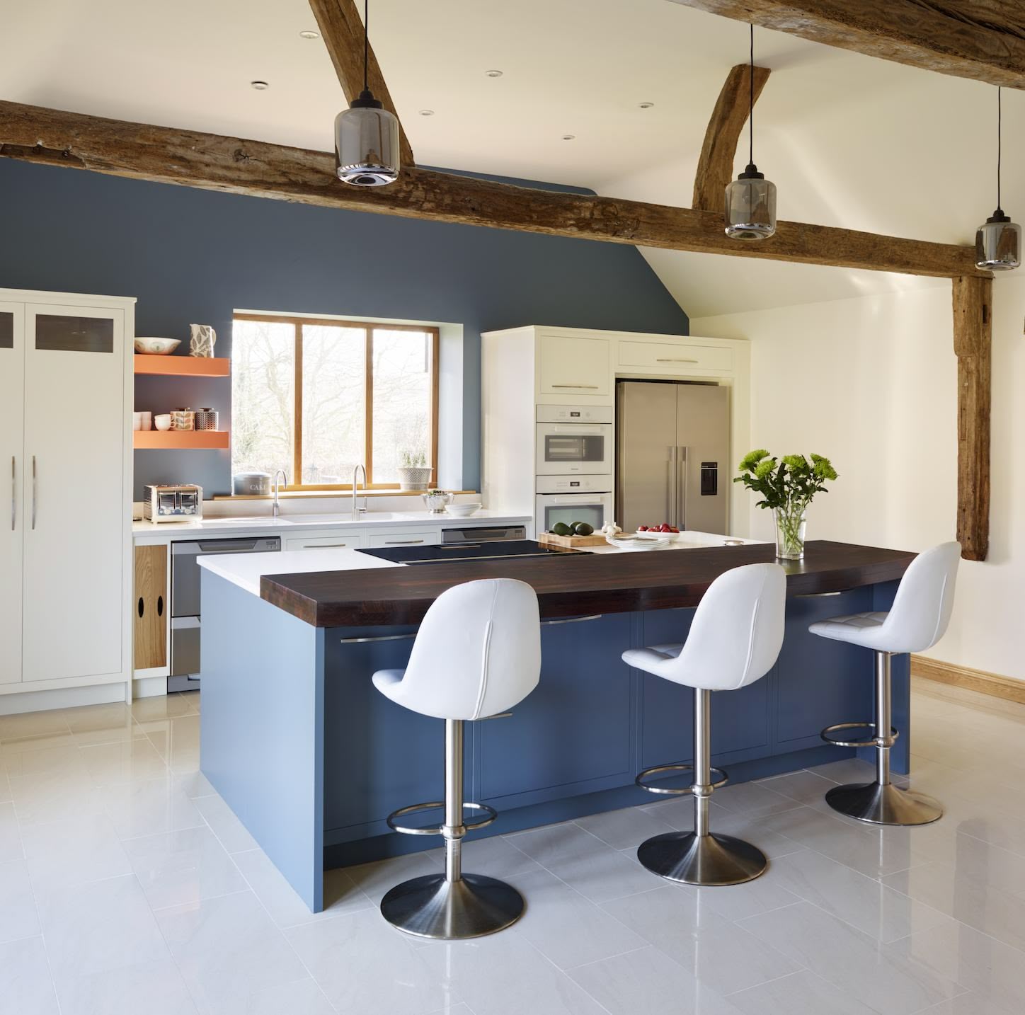 Blue kitchen island with white worktop and black extension featuring white stools