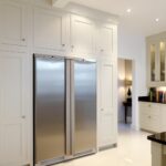 White Shaker kitchen cabinetry surrounding American style fridge