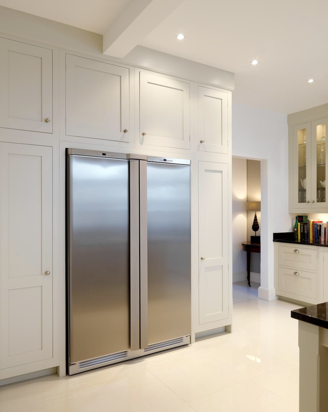 White Shaker kitchen cabinetry surrounding American style fridge