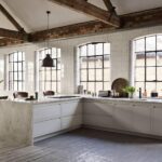 Industrial style kitchen with cream Linear Edge kitchen cabinetry and marble worktop next to open plan dining area