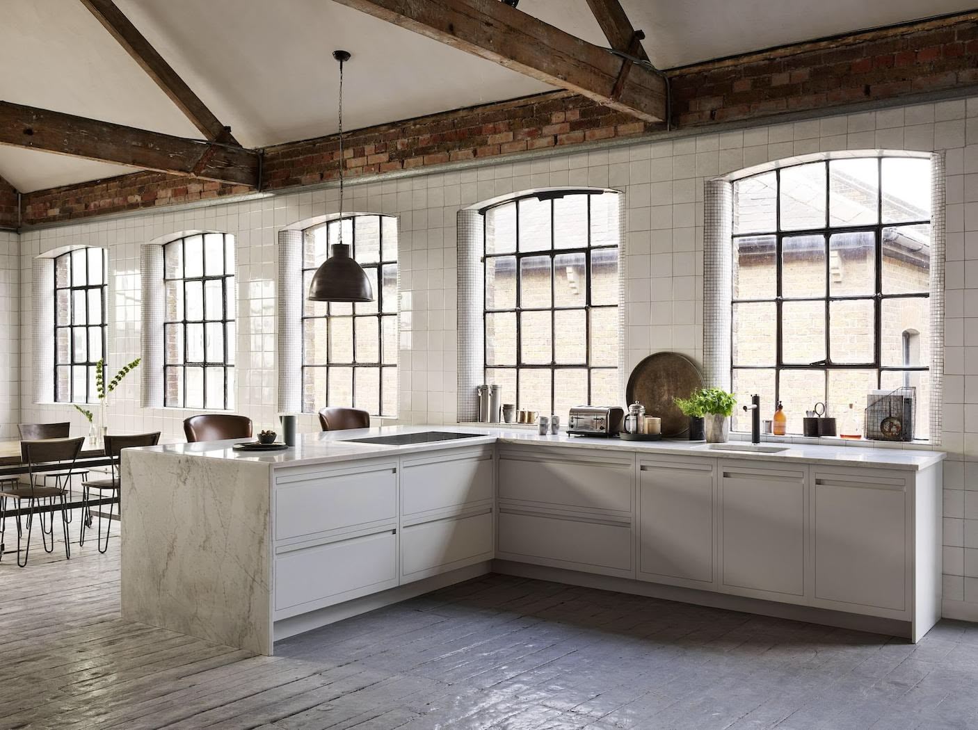 Industrial style kitchen with cream Linear Edge kitchen cabinetry and marble worktop next to open plan dining area
