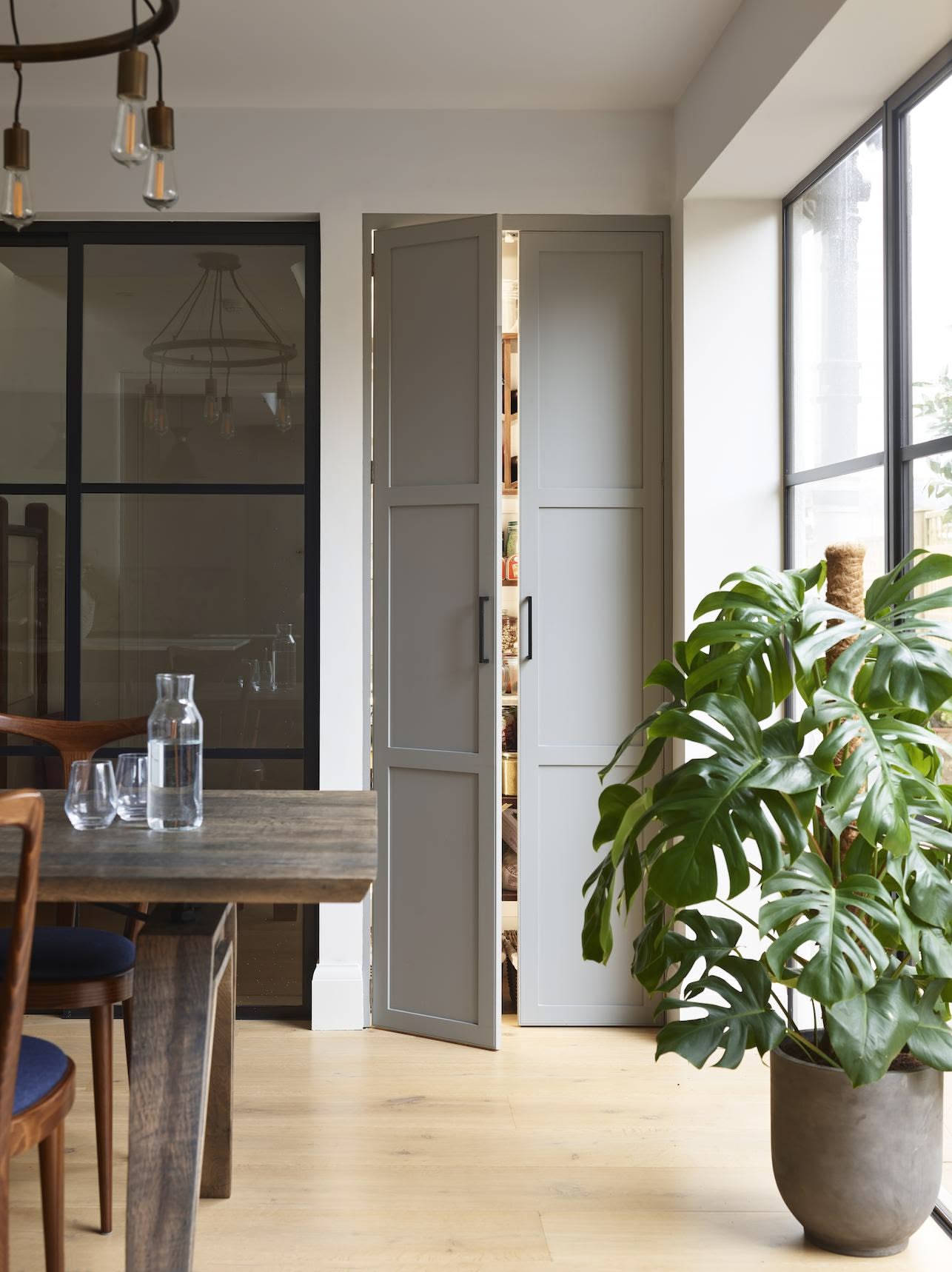 Large pantry with double doors next to an open plan dining area