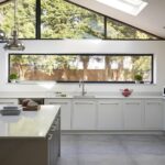 White minimalist kitchen design with long windows overlooking the garden