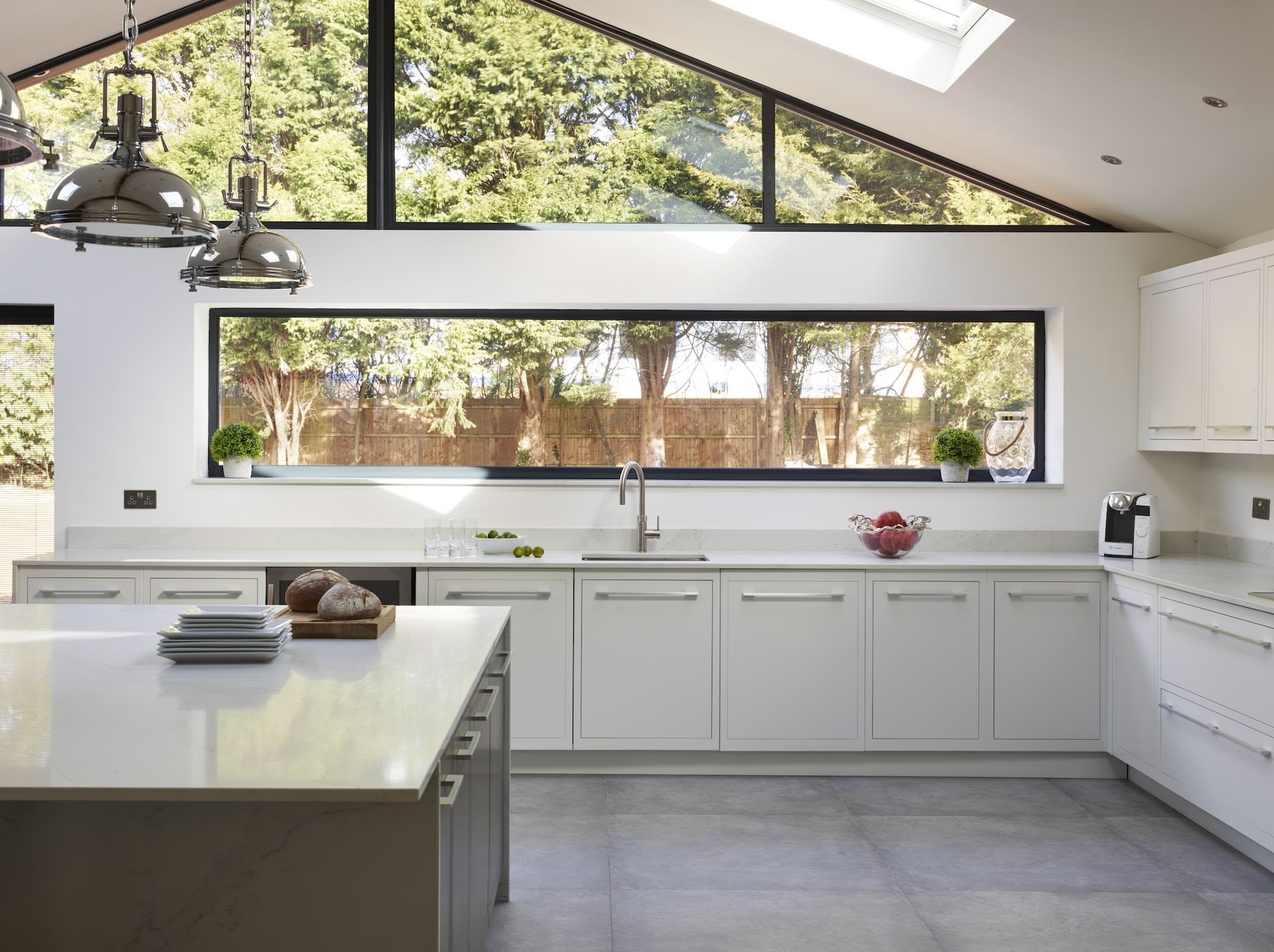 White minimalist kitchen design with long windows overlooking the garden