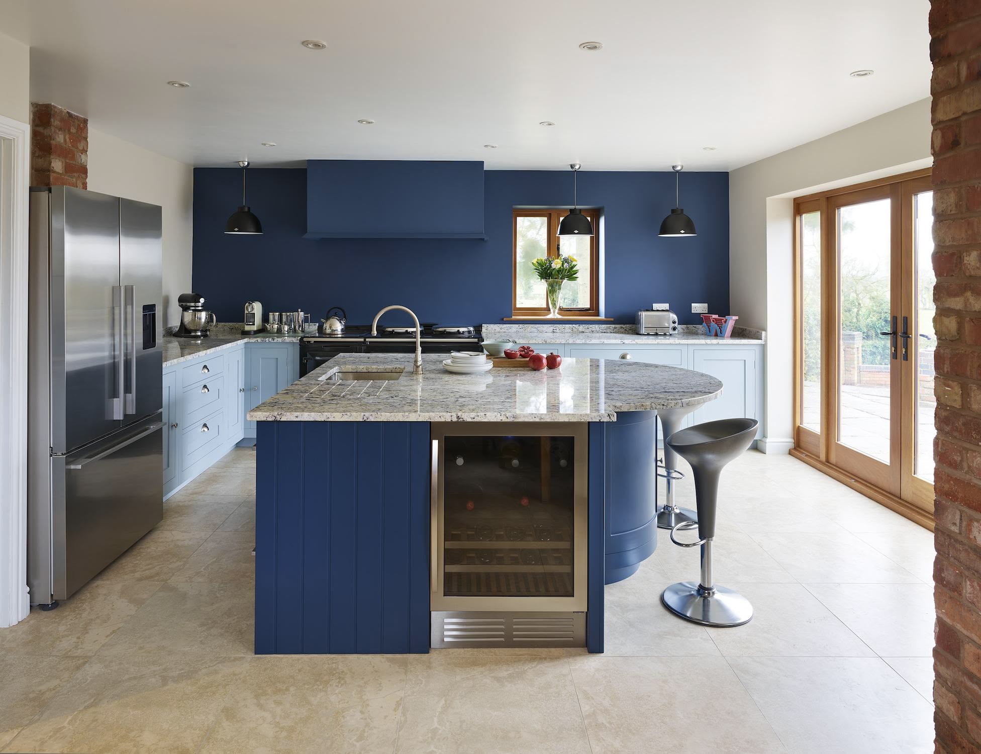Blue curved kitchen island with granite worktop with blue Shaker kitchen cabinetry