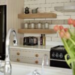 White Kitchen island worktop with integrated sink featuring silver tap and grooved drainer overlooking beige Shaker kitchen cabinetry