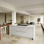 Open plan white Linear kitchen with walnut breakfast bar looking onto living area