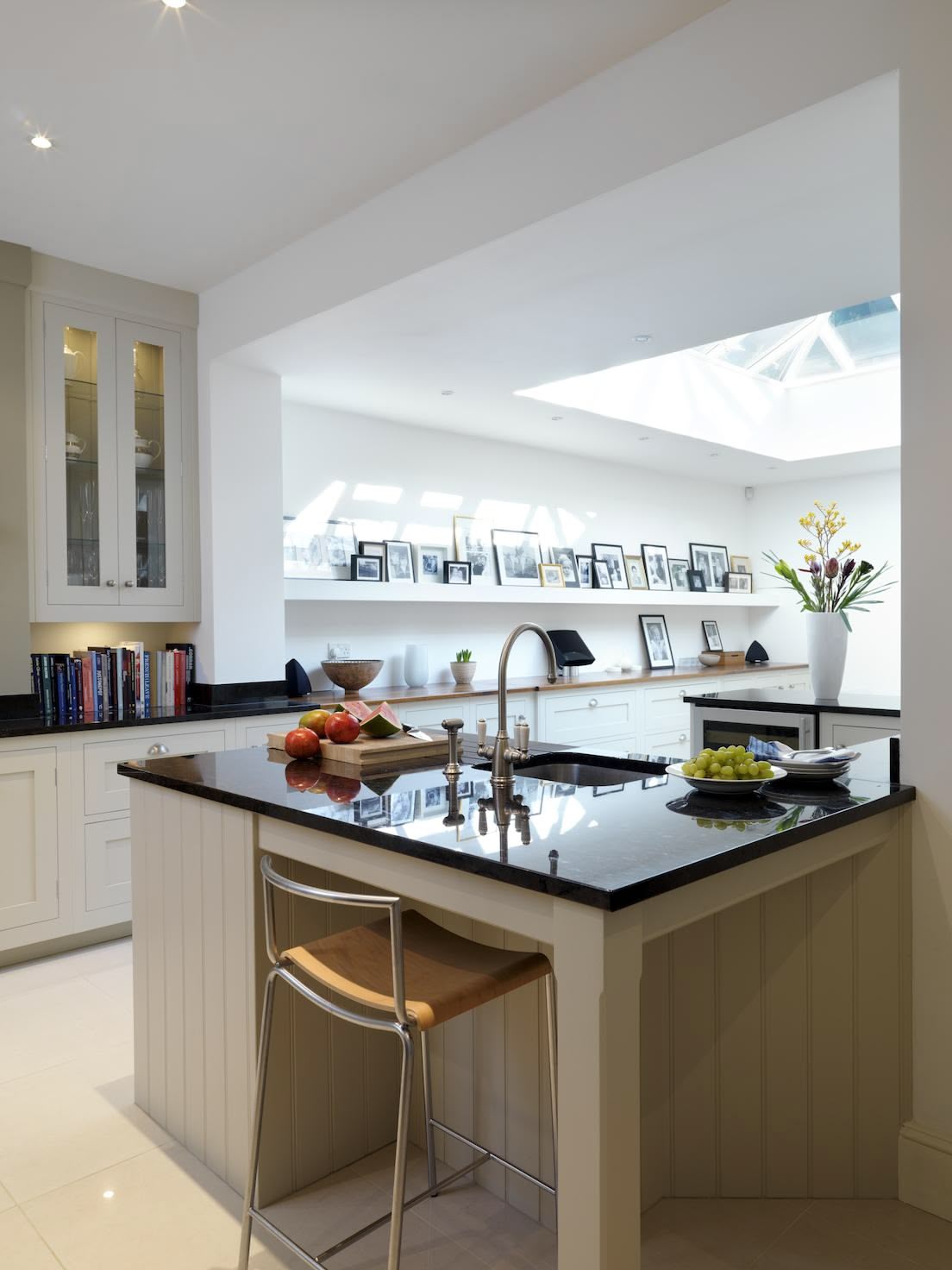 White Shaker kitchen island with black worktop featuring integrated sink and bar stool