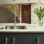 Silver sink integrated into a cream worktop with dark grey kitchen cabinetry and silver handles