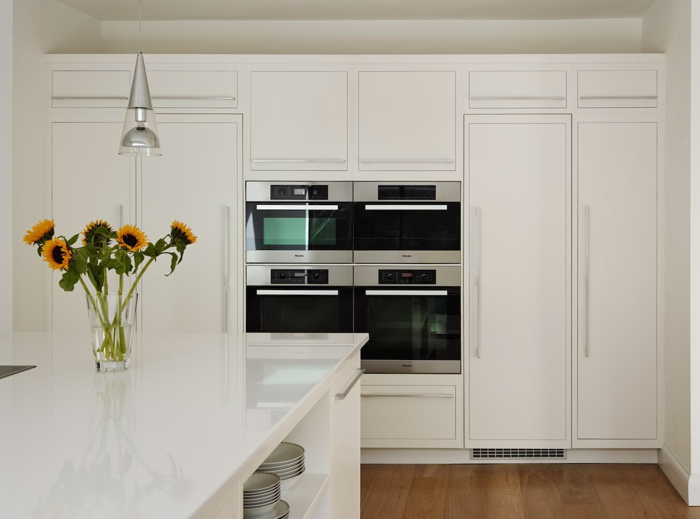 Linear kitchen design featuring bright white kitchen cabinetry and integrated appliances