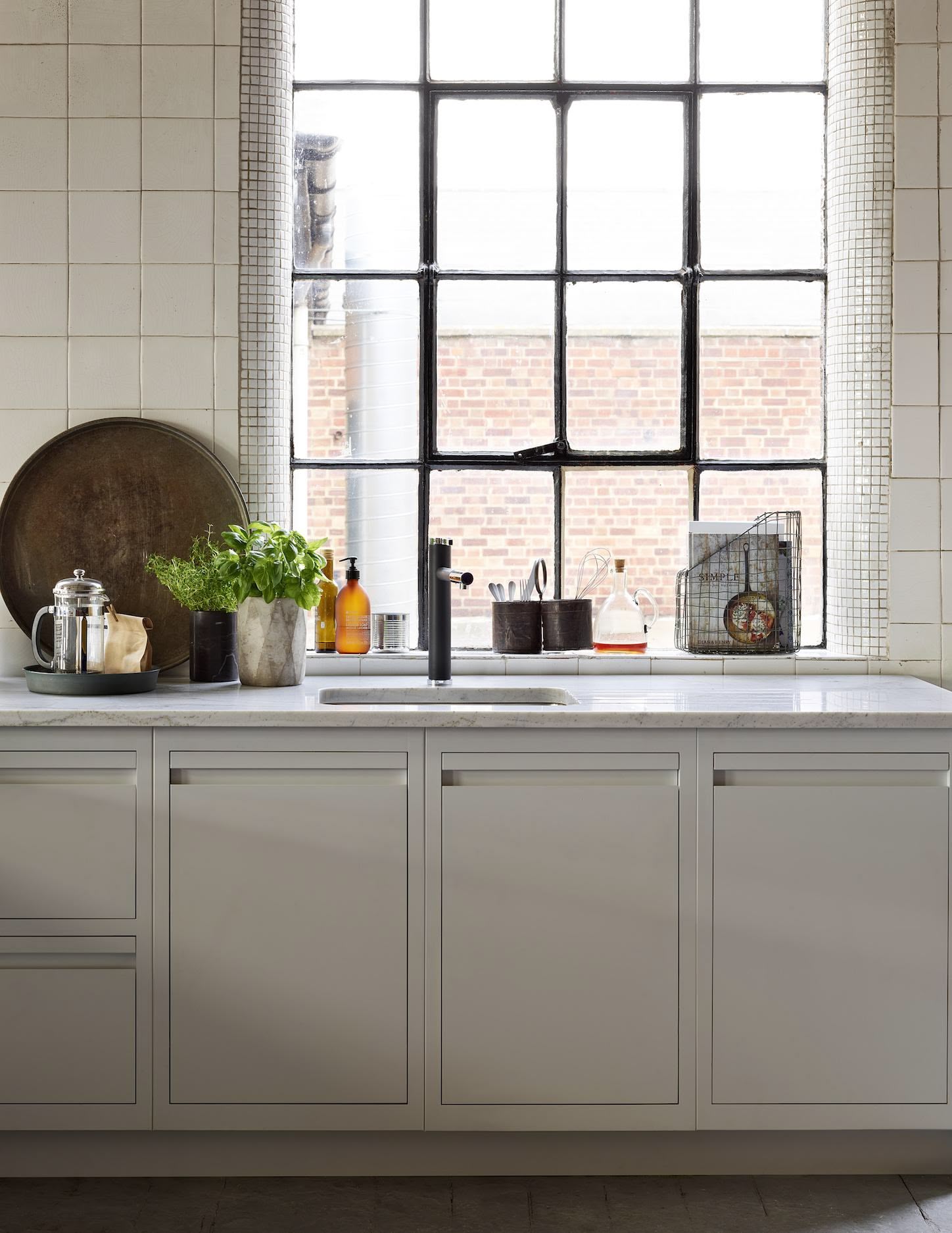 Cream Linear Edge kitchen cabinetry with white marble worktop featuring a white sink with dark tap against a window