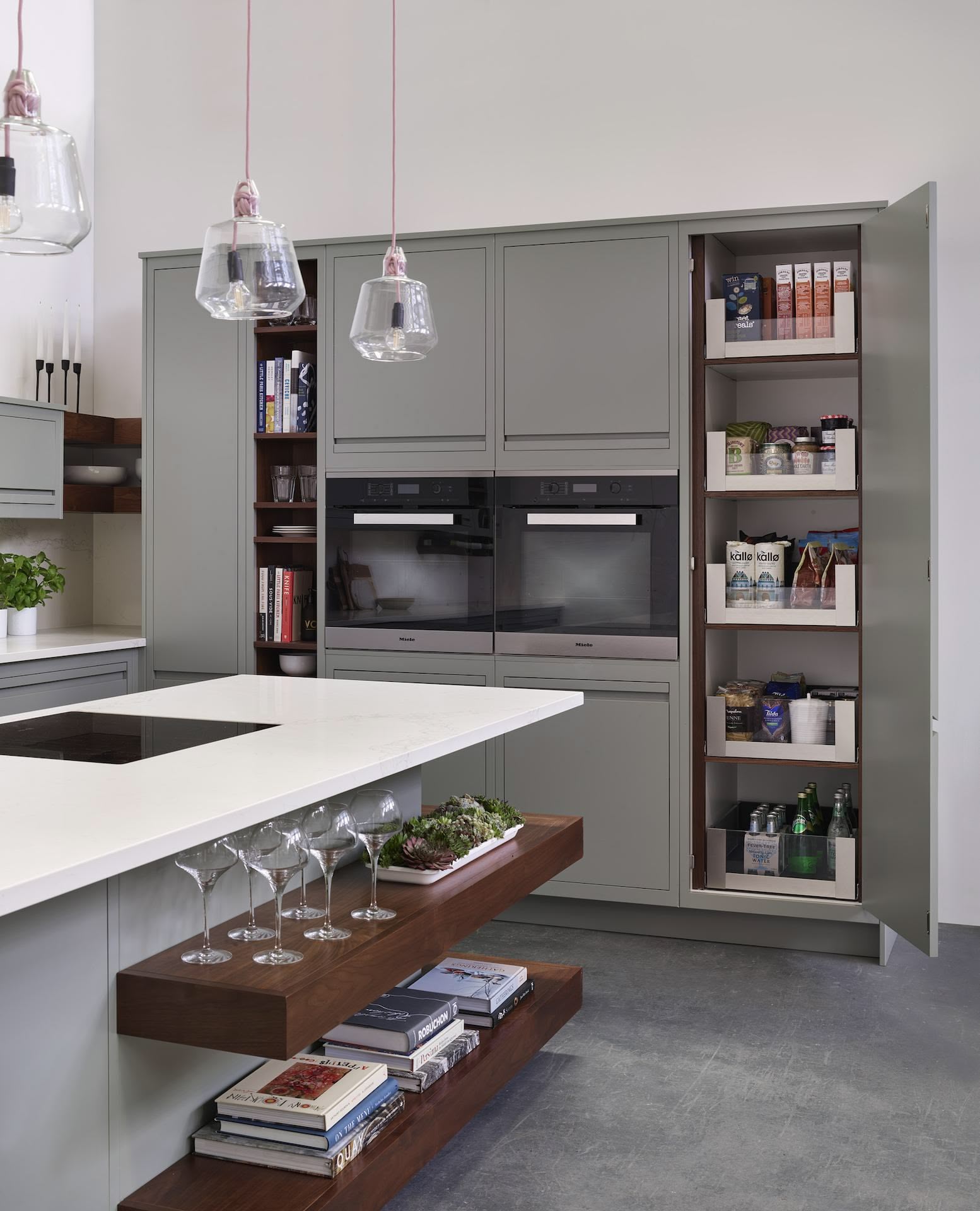 Grey tall pantry next to kitchen oven and cabinetry, open to show organised storage