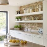 Cream Linear Edge kitchen cabinetry with natural bricked wall and cream shelving