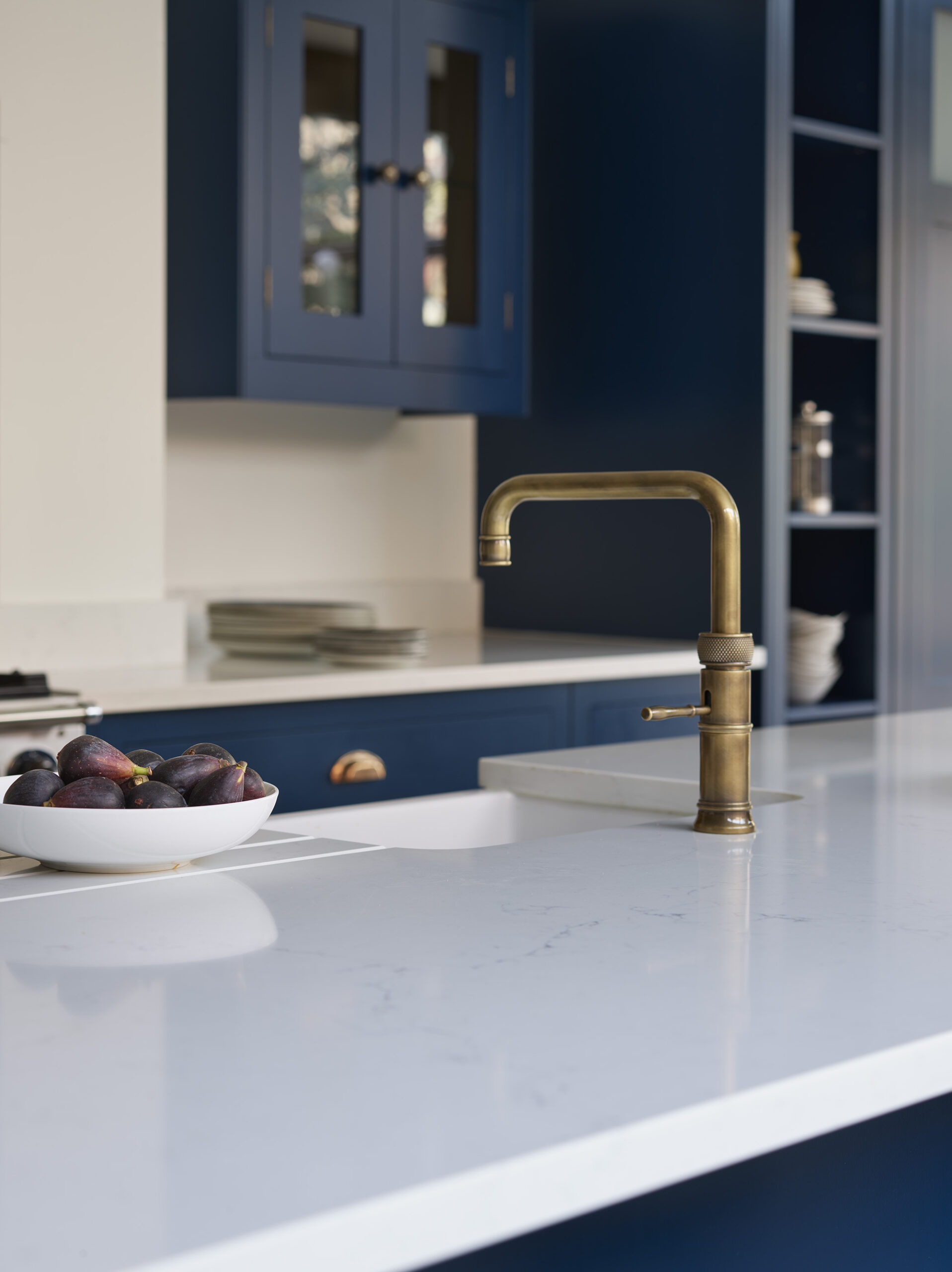Navy Shaker kitchen cabinetry with white worktops featuring integrated sink and brass tap