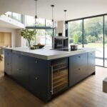 Blue kitchen island with white worktop in front of an open plan dining area