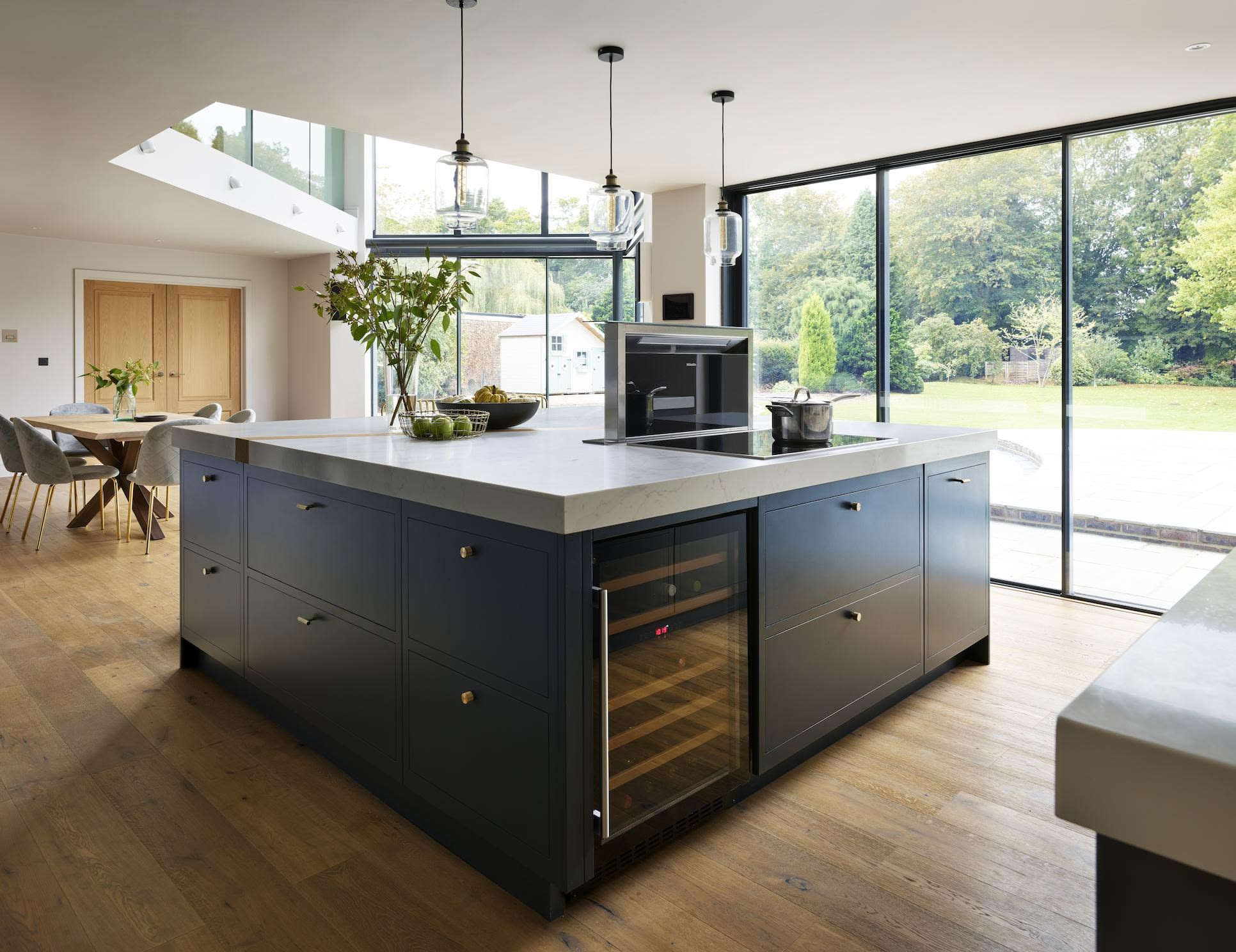 Blue kitchen island with white worktop in front of an open plan dining area