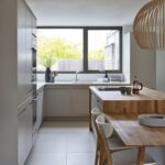 Natural beige Linear Edge kitchen cabinetry and wooden kitchen island with open plan dining area