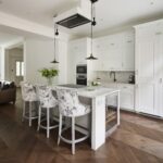 White Original kitchen cabinetry and white kitchen island with marble worktop, integrated hob and white and grey stools