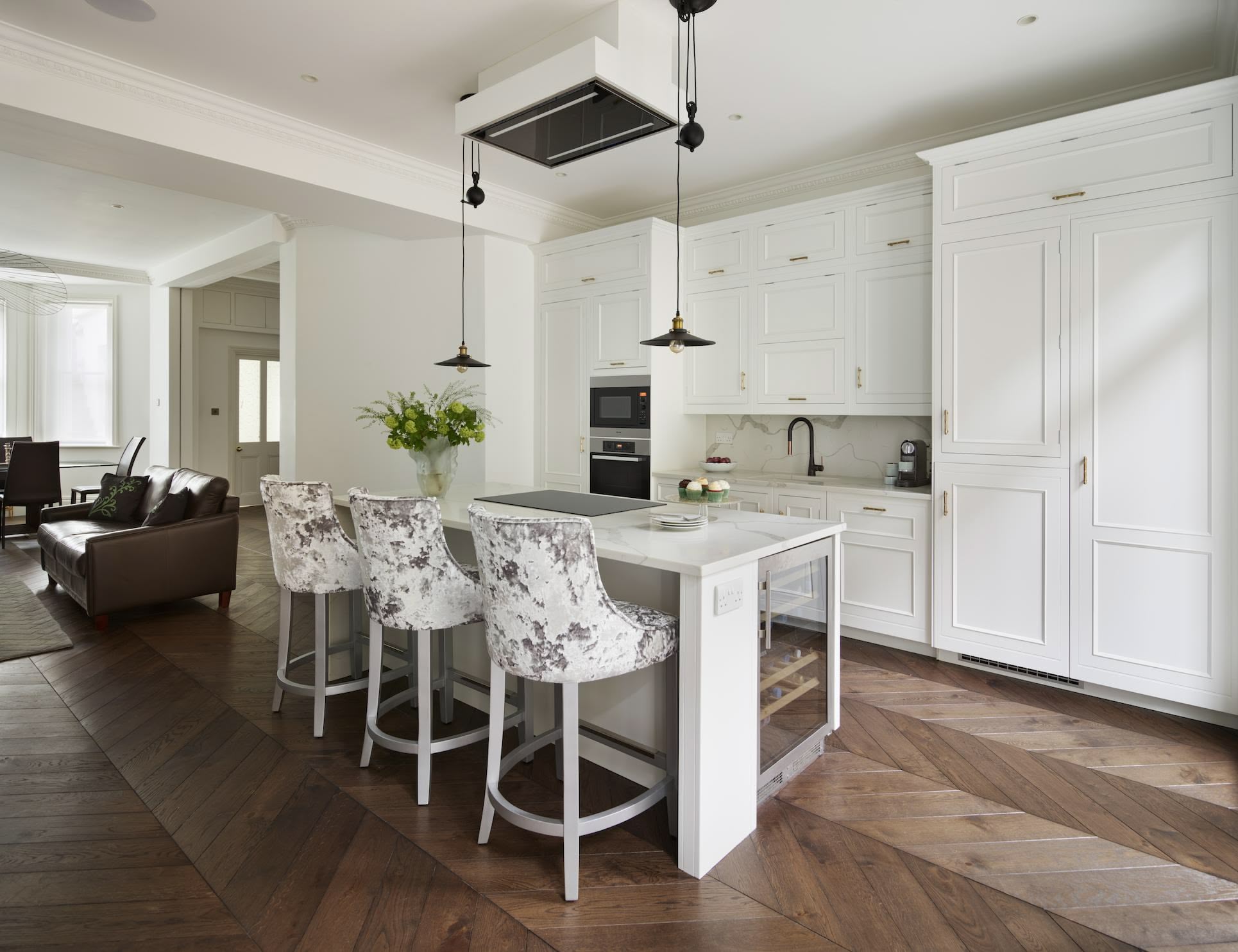 White Original kitchen cabinetry and white kitchen island with marble worktop, integrated hob and white and grey stools