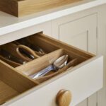 Beige Shaker kitchen drawer open to show oak interior