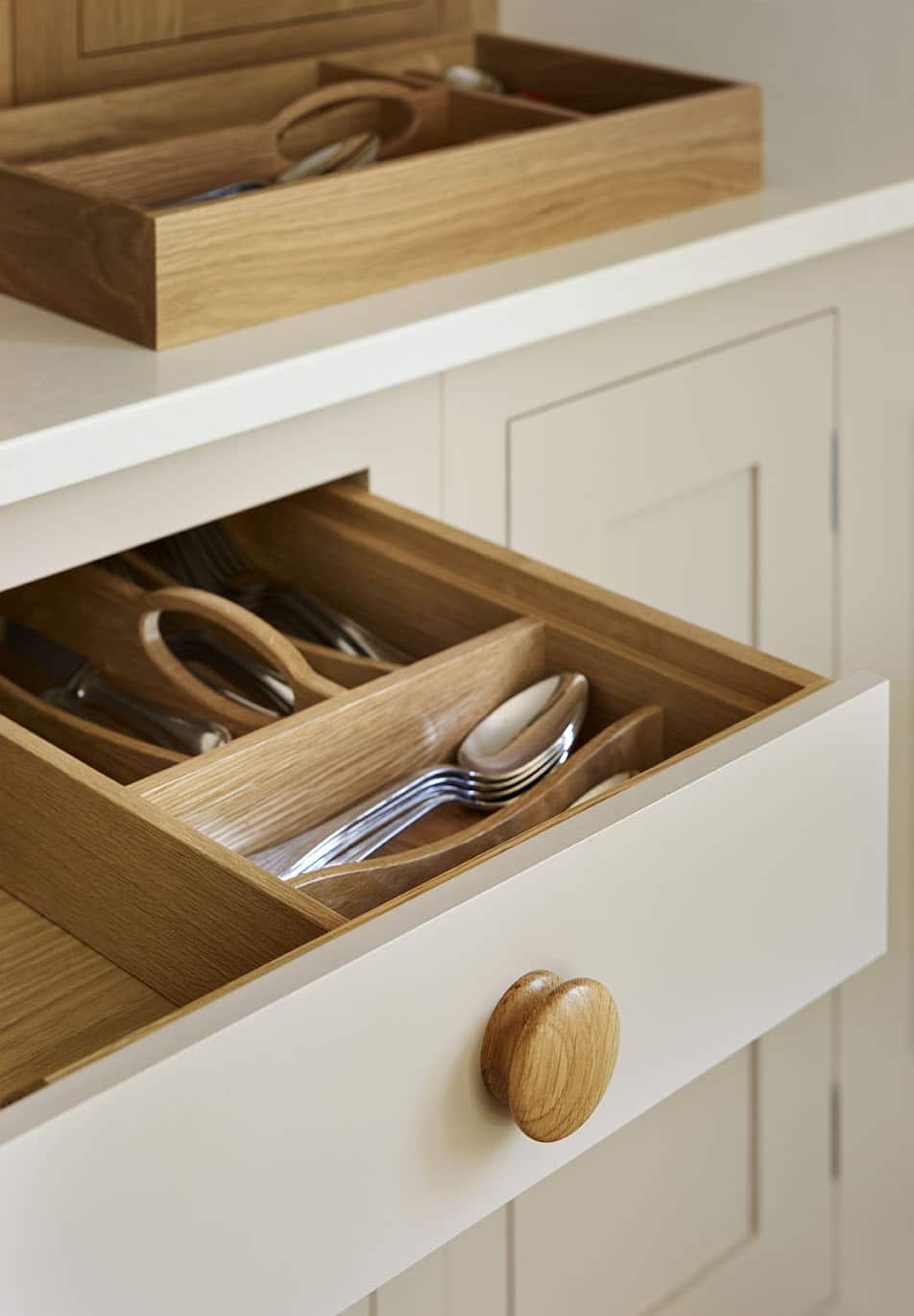 Beige Shaker kitchen drawer open to show oak interior
