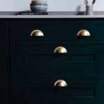 Closeup of rich green Shaker kitchen cabinetry with brass handles