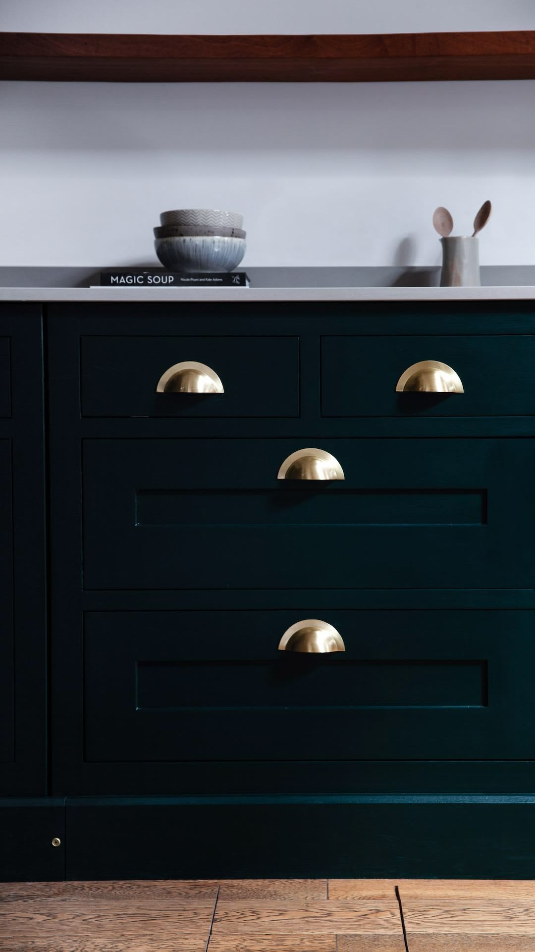 Closeup of rich green Shaker kitchen cabinetry with brass handles