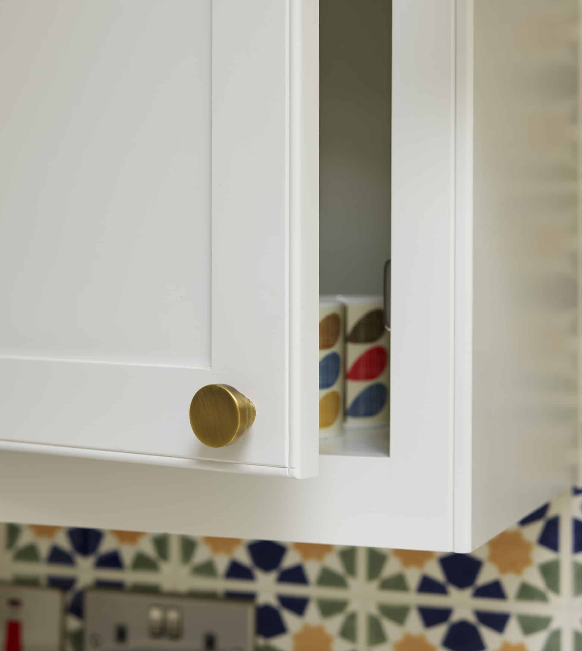 Close up of a white Arbor kitchen cupboard with a gold round handle