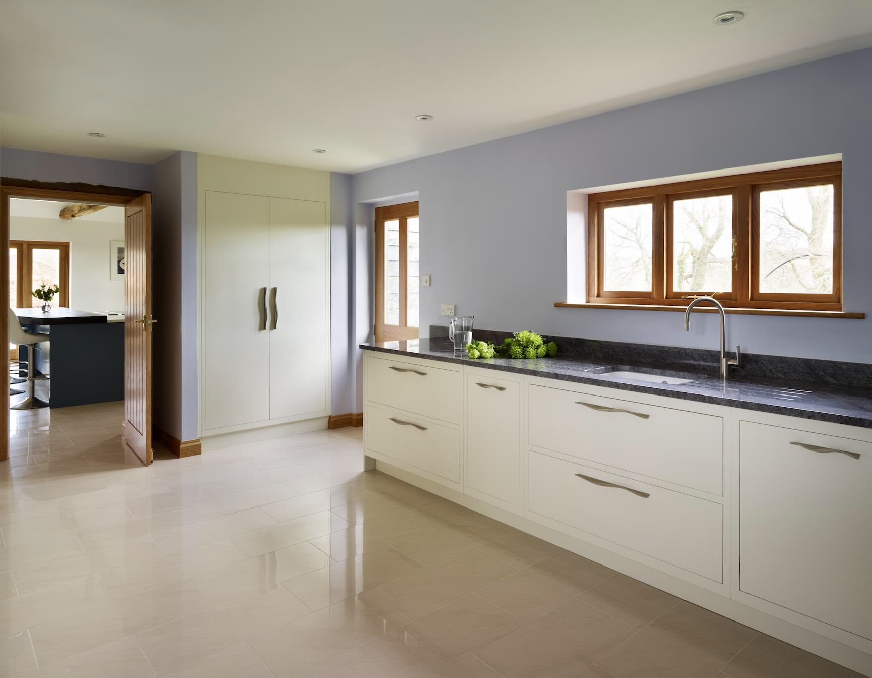 White Linear kitchen cabinetry with black worktops in a barn conversion