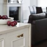 Closeup of white kitchen island drawer with brass handle framed by white marble waterfall edge worktop